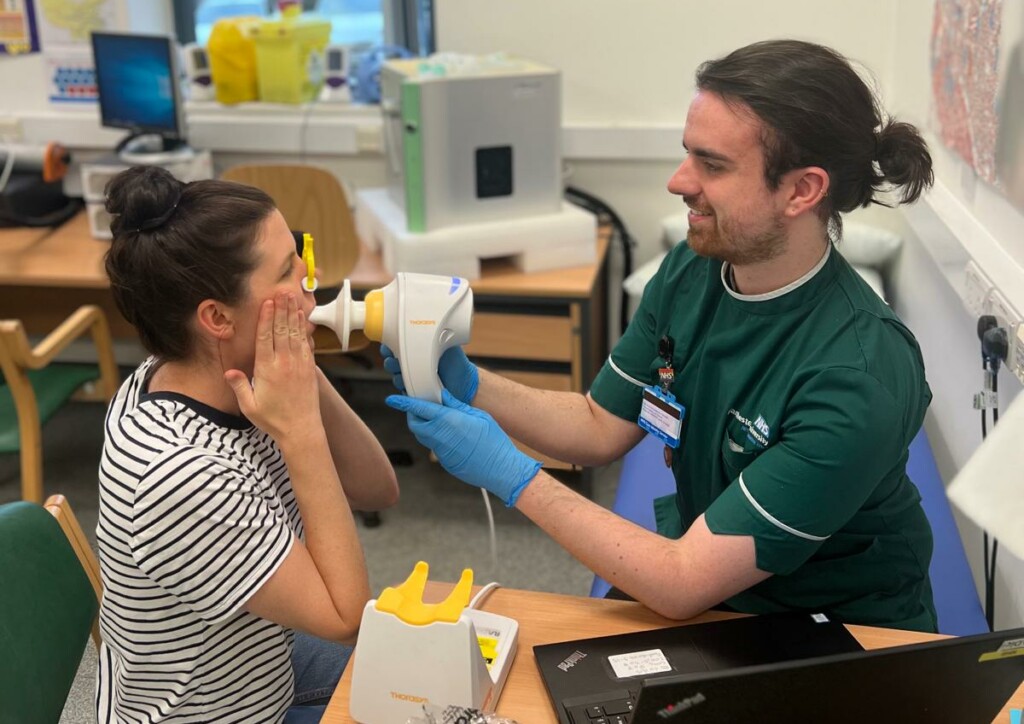 A clinician holding a machine which a study participant is breathing into