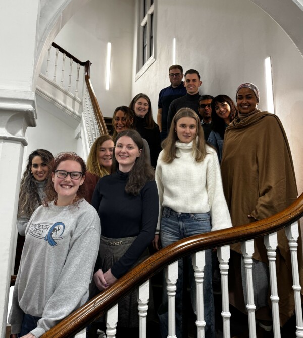 12 people including Manchester BRC PhD students standing on a staircase. They are smiling at the camera.